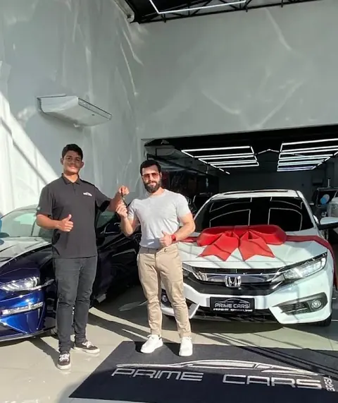 Vendedor da Prime Cars entregando um Honda Civic com laço vermelho ao cliente Ruy Beck